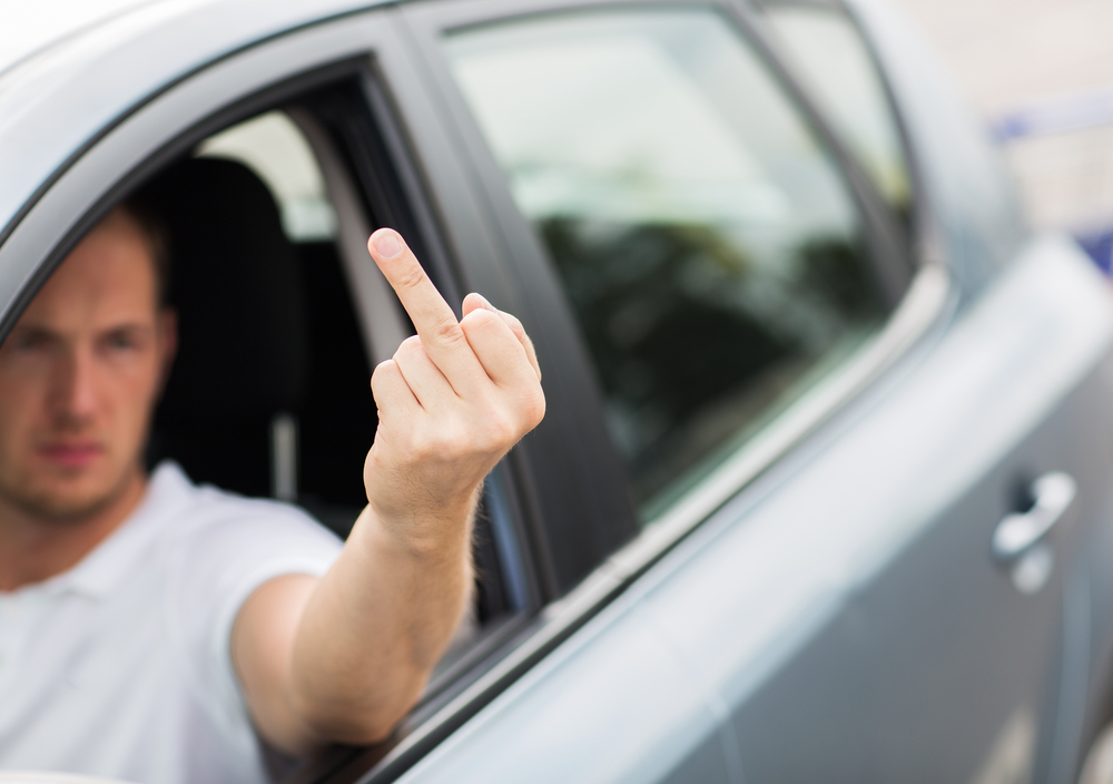 Man sticking rude finger from car