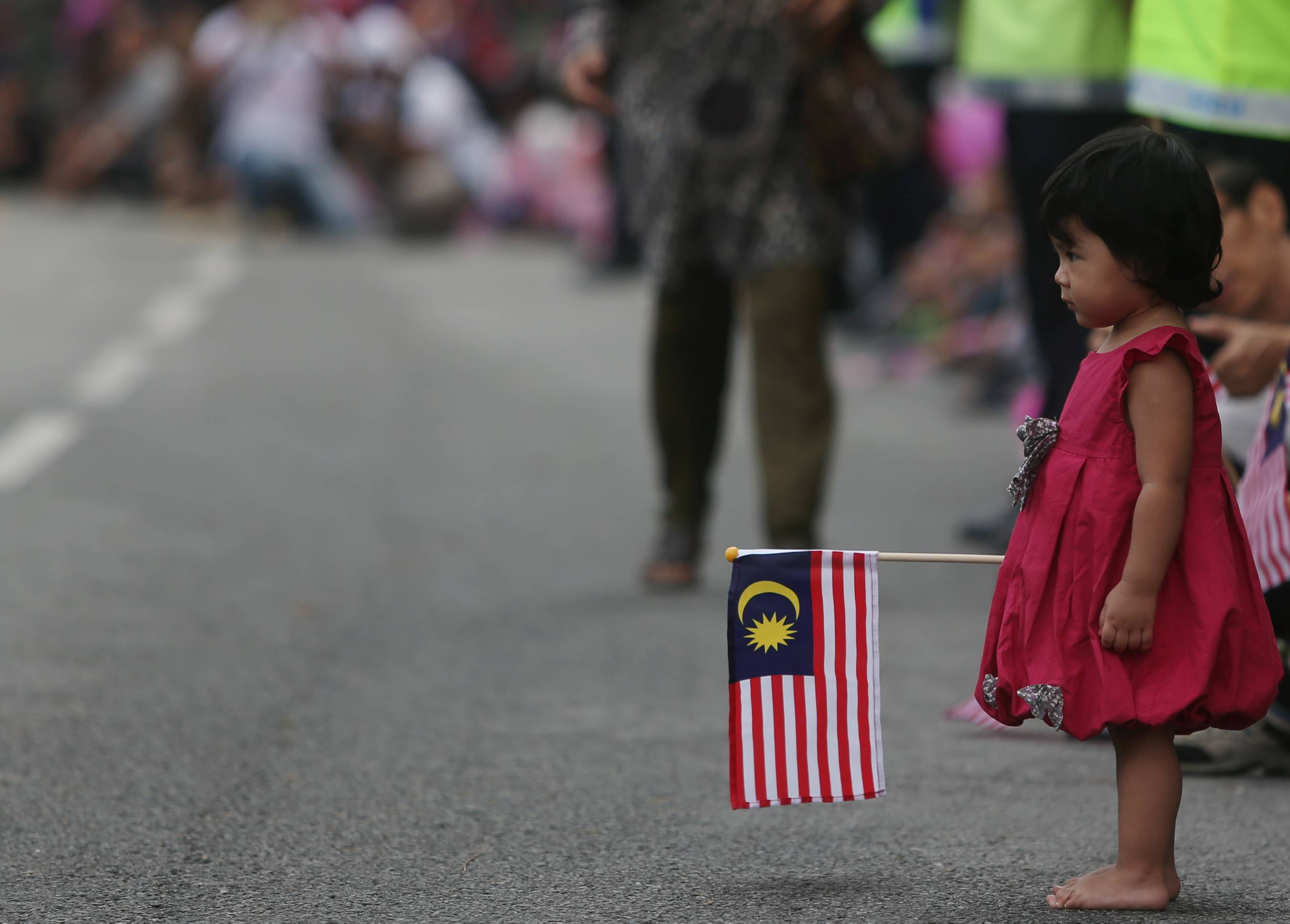 Toddler carrying Malaysian flag on street