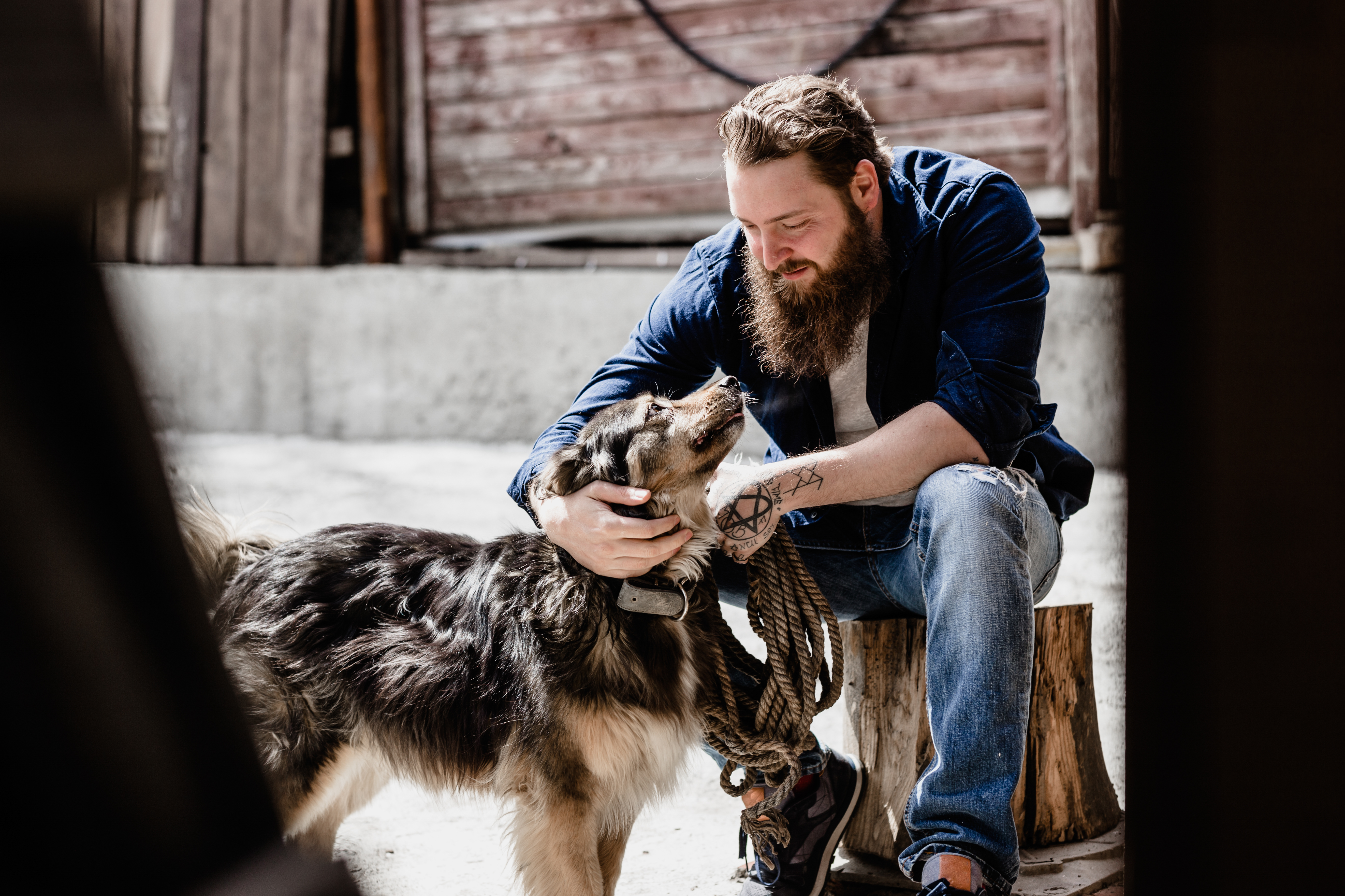 Man with beard sitting in front of his dog