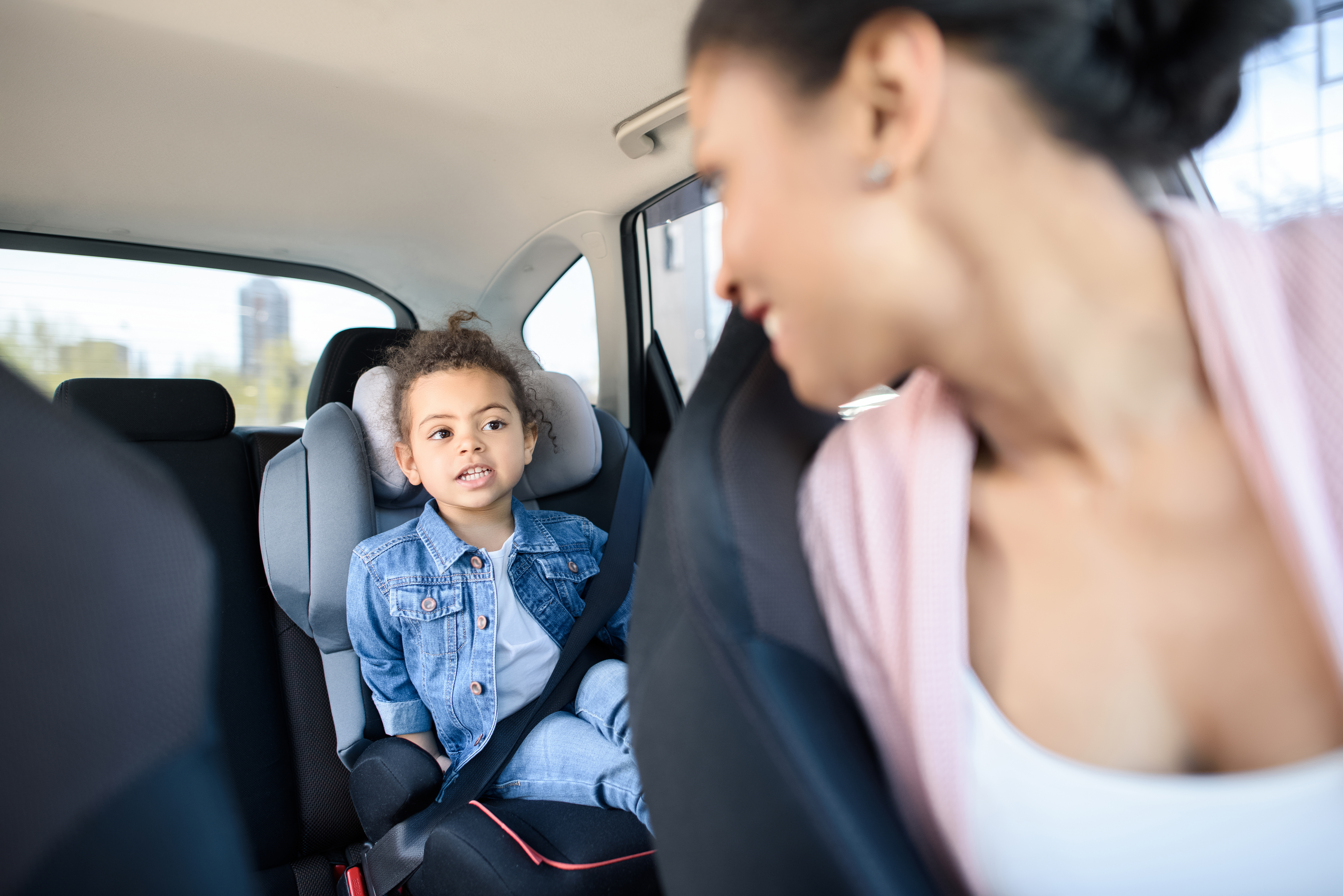Child in back seat of car with mother driving